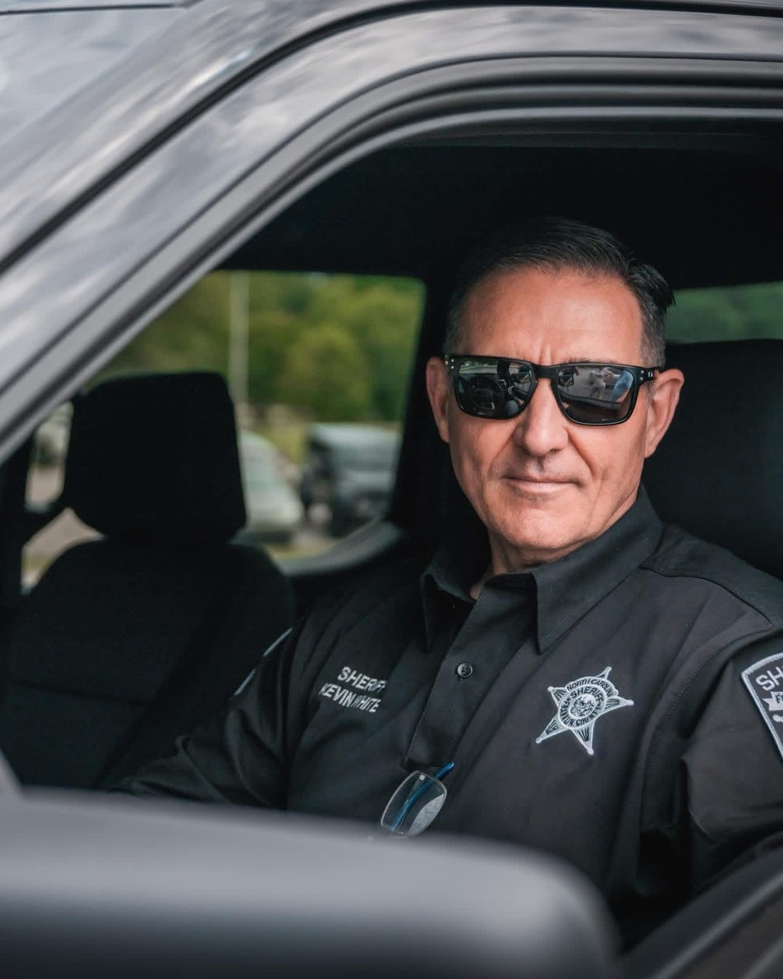 Sheriff Kevin White in a patrol vehicle, wearing sunglasses and a Wake County Sheriff uniform